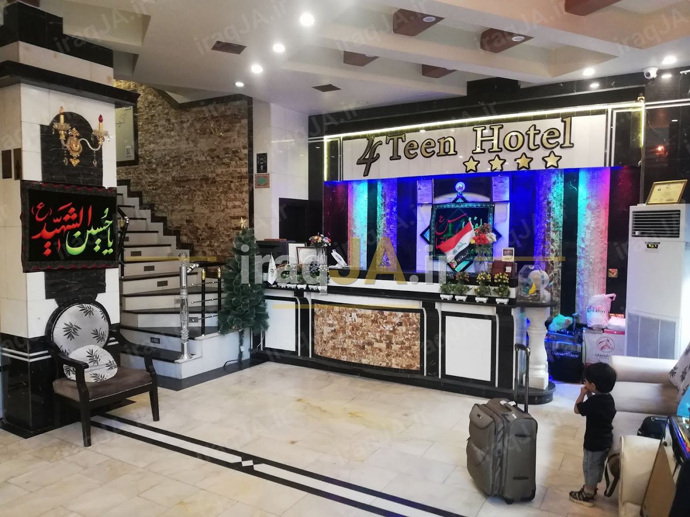 پذیرشِ هتل با تابلوی «4Teen Hotel»، نورپردازیِ رنگی و پلهٔ کنارِ لابی