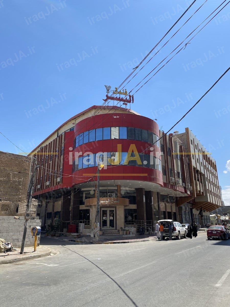 ساختمان نبشی هتل الیسر با نمای قرمز و تابلوی عربی روی بام