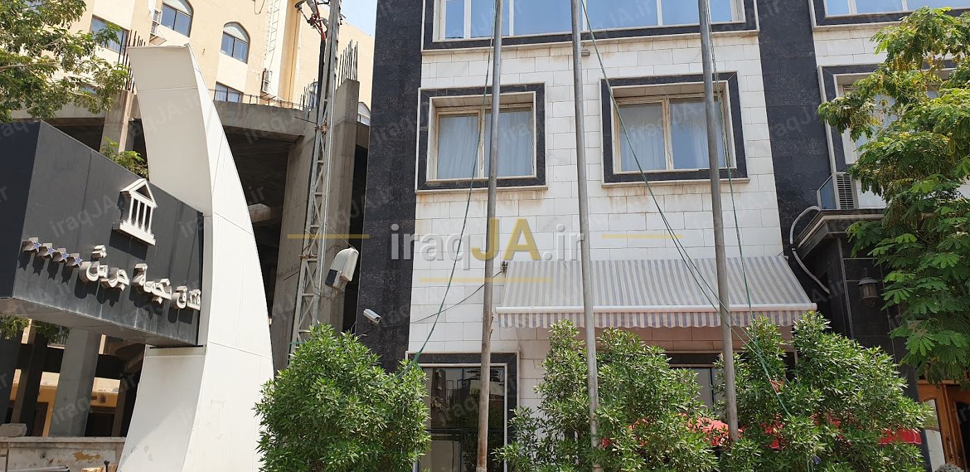 نمای بیرونی ساختمان سنگی هتل با تابلوی سردر و درختان جلوی ورودی