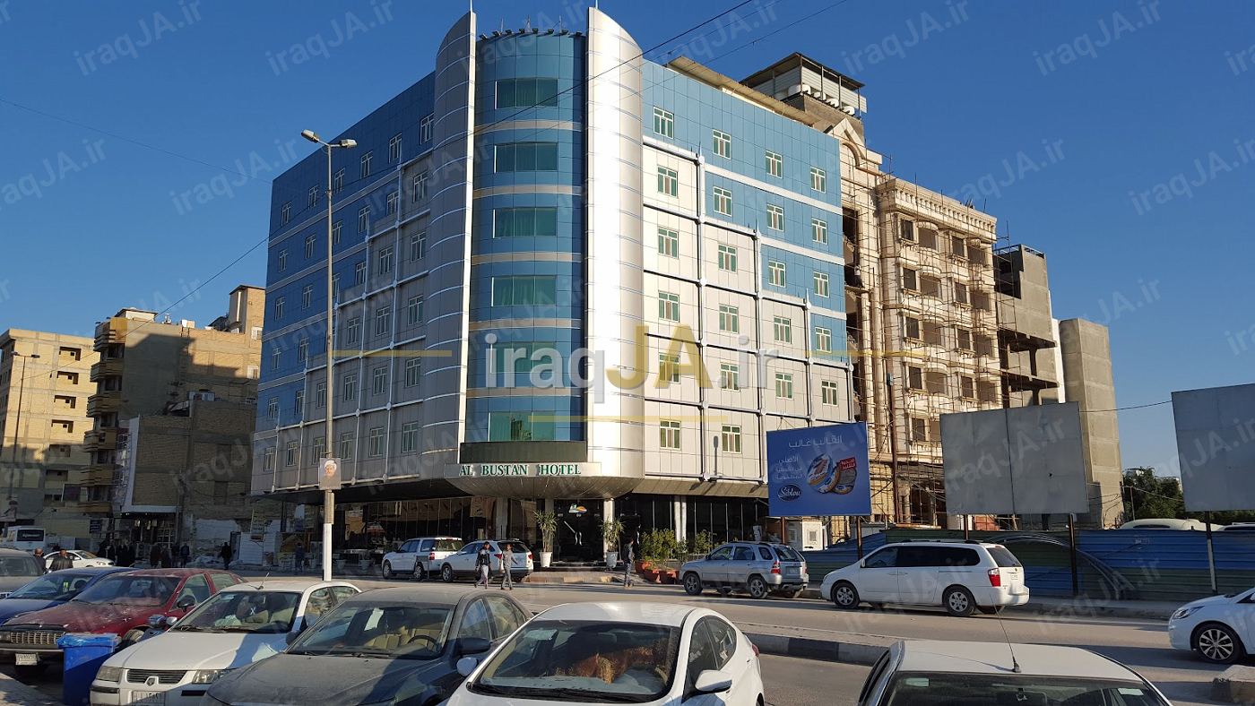 نمای بیرونی هتل با نمای شیشه‌ای آبی و خیابان پرتردد روبه‌رو